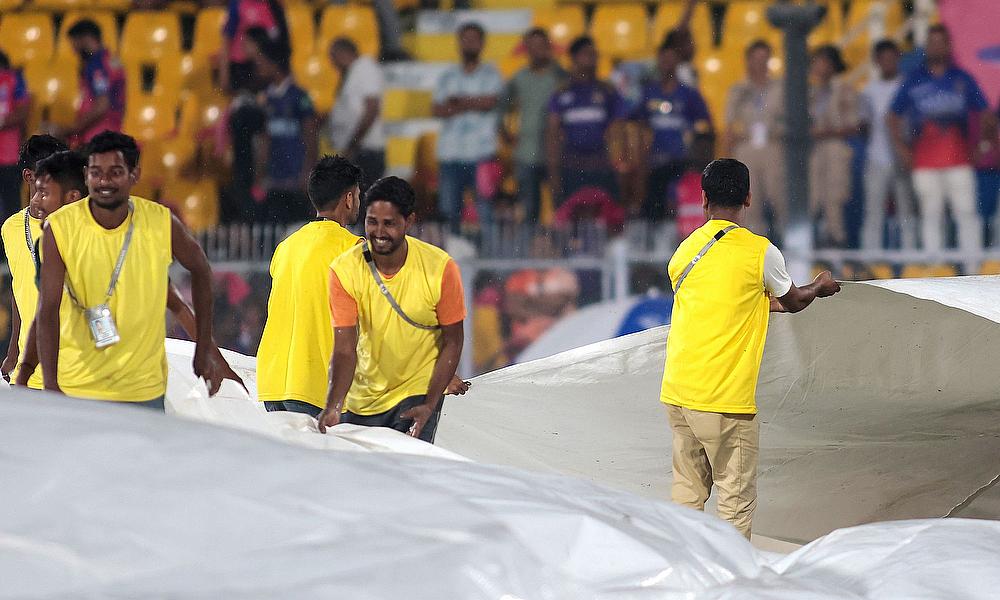 Ground staff brings more covers on the ground as rain delays the IPL